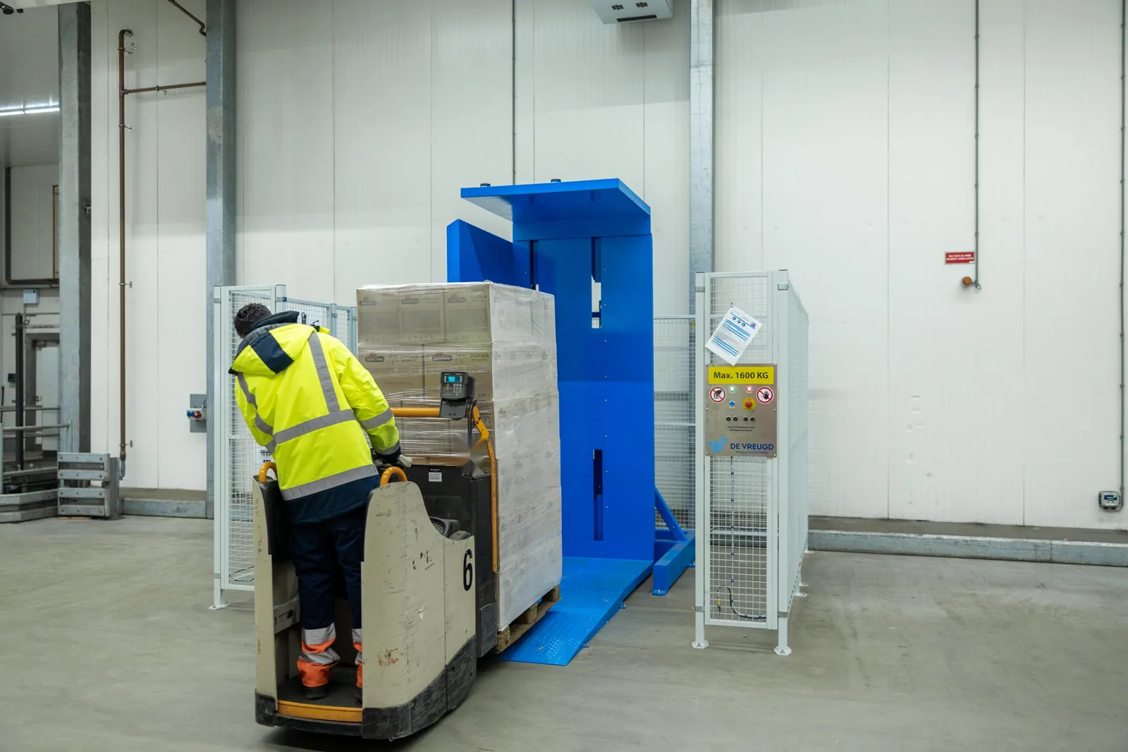 Employee drives an electric pump truck with a pallet up the ramp of the pallet inverter PalletRotator EPT